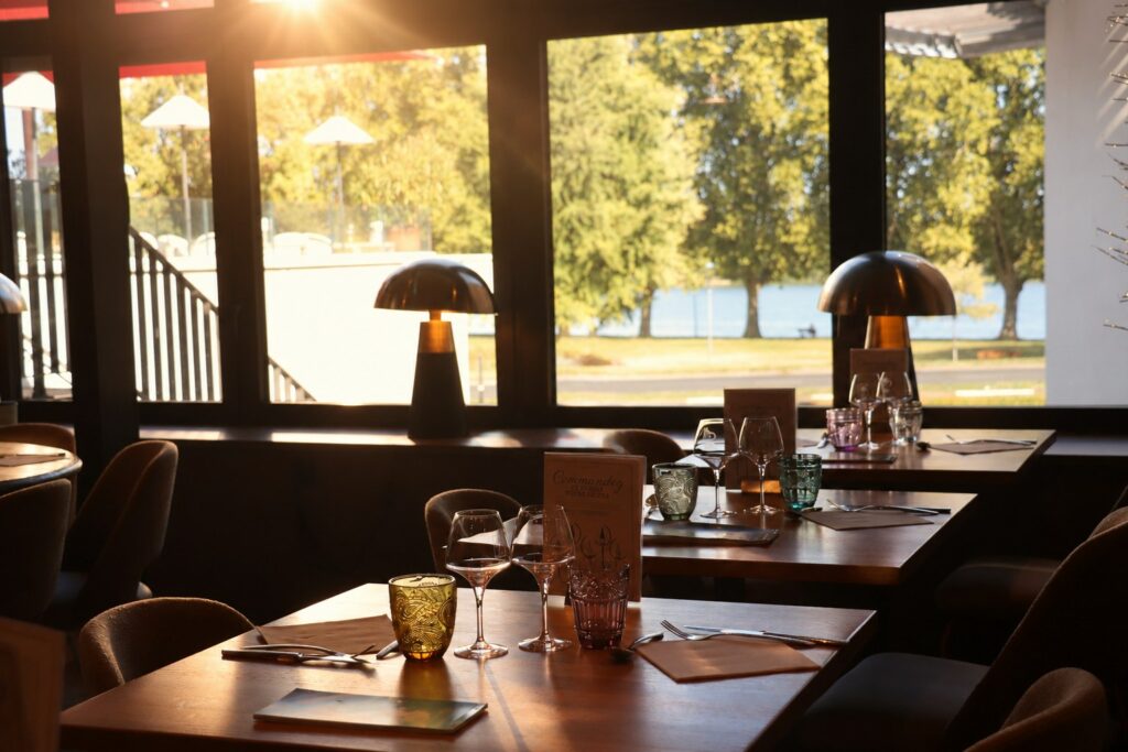 La Verrière au coucher du soleil : tables dressées, lampes champignon et vue sur les arbres