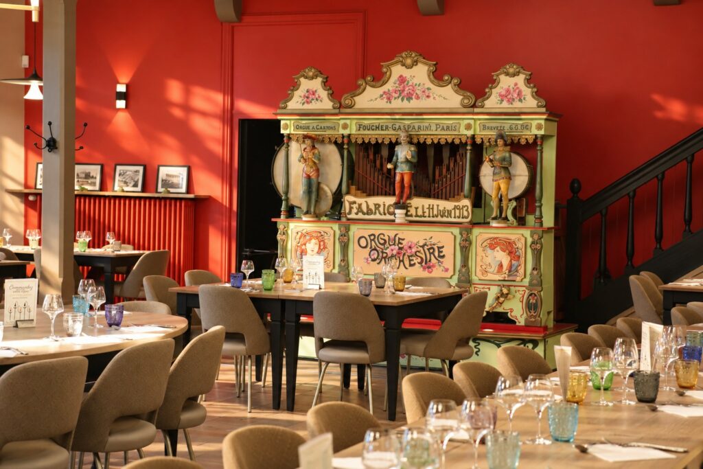 L'Orgue & le Comptoir : l'orgue à cartons Foucher-Gasparini de 1913 devant un mur rouge, entouré de tables dressées